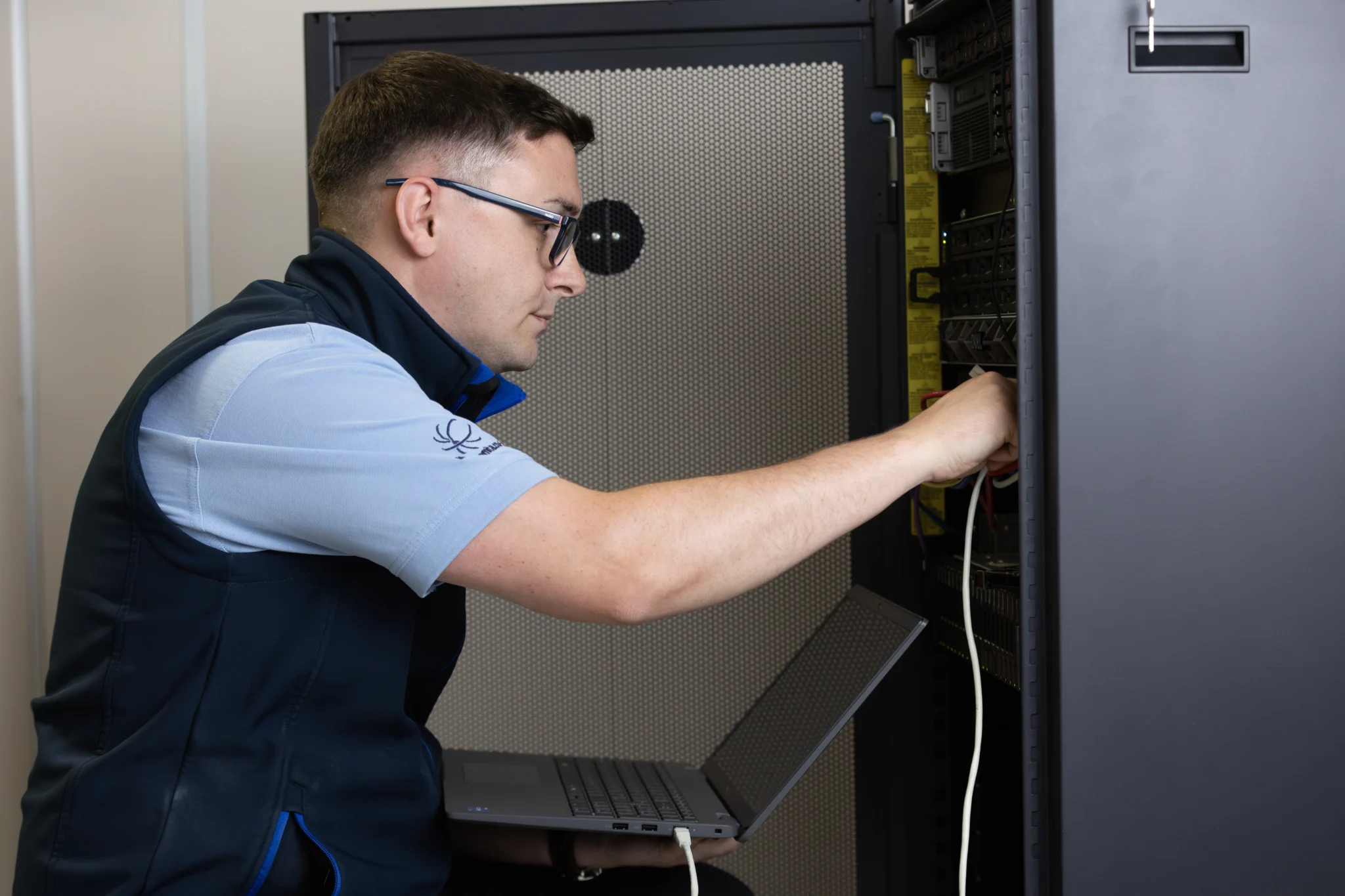 a man connecting laptop into a server rack
